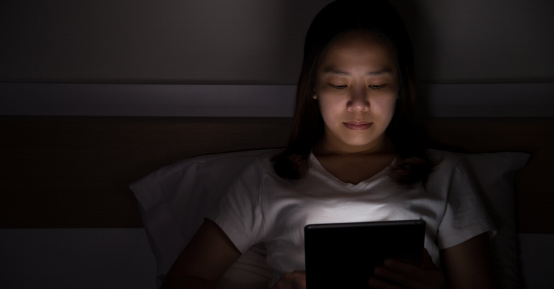 woman using tablet in bed at night
